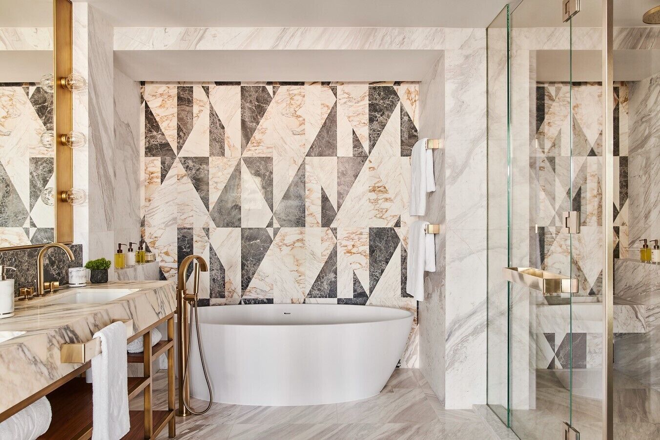 Un baño moderno con una bañera independiente, paredes de mármol y cabina de ducha de vidrio.