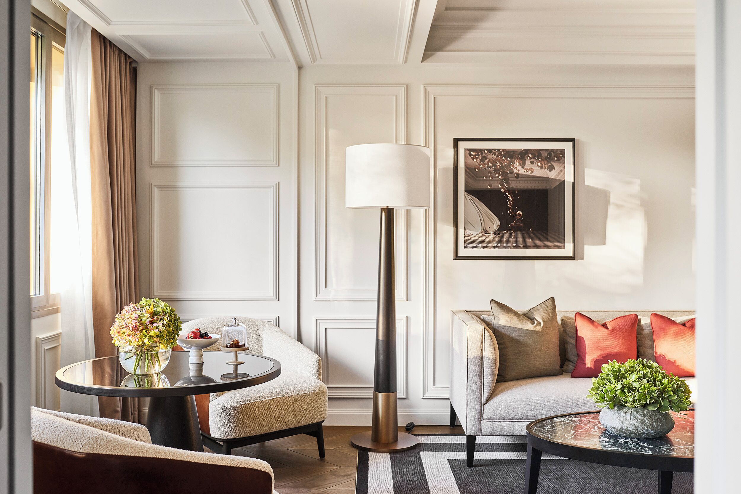 Un salon moderne avec un canapé, des fauteuils, une table basse, un lampadaire et un tableau accroché au mur.