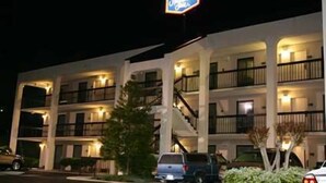 A multi-story motel with balconies, a parking lot, and a neon sign. - Hampton Inn Dalton (Dalton)