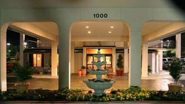 A hotel entrance with a central fountain, a number '1000' above the doors, and a well-lit facade. - Hampton Inn Dalton (Dalton)