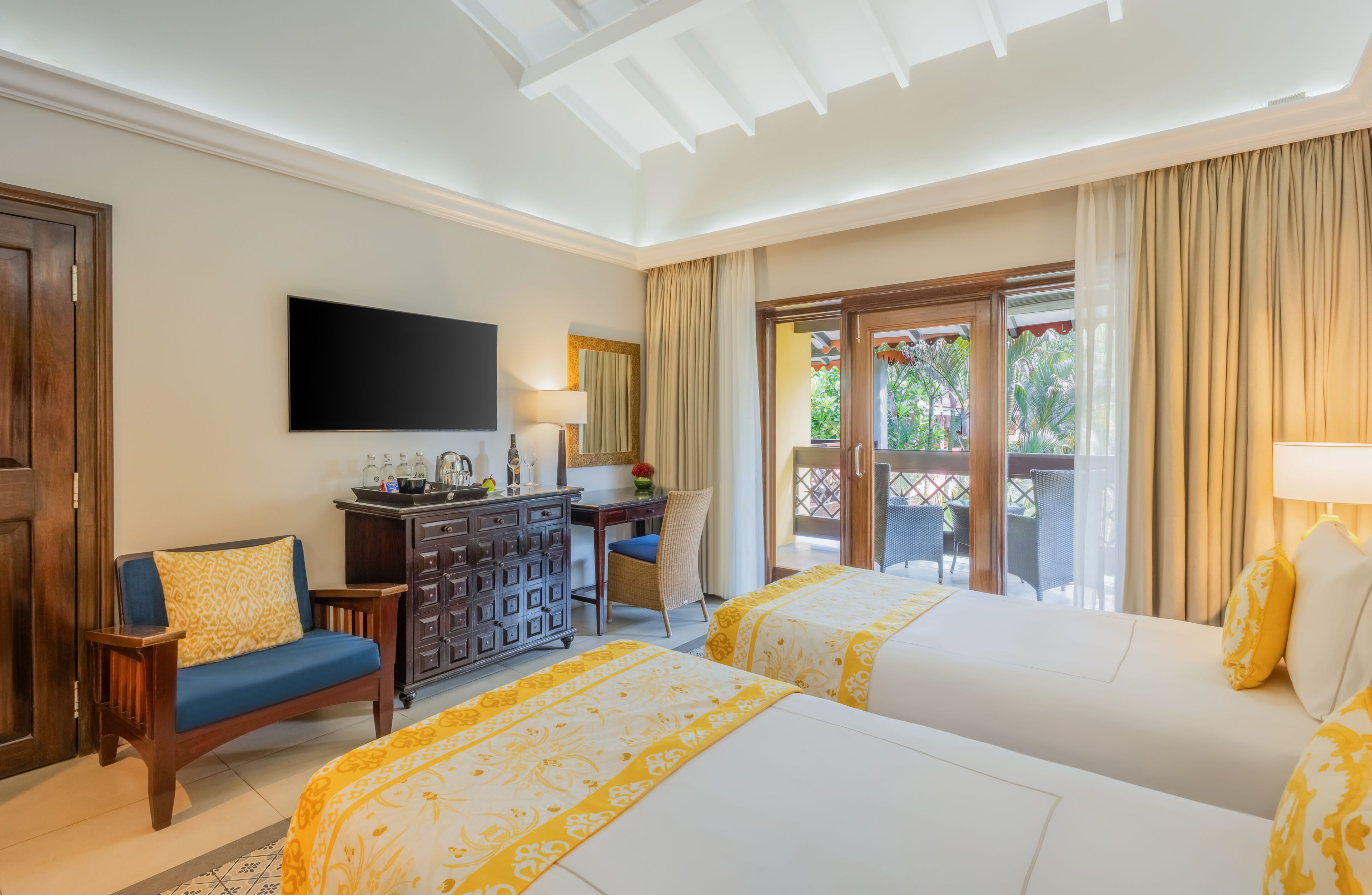 A hotel room with two beds, a desk, a television, and a view of the outdoors.