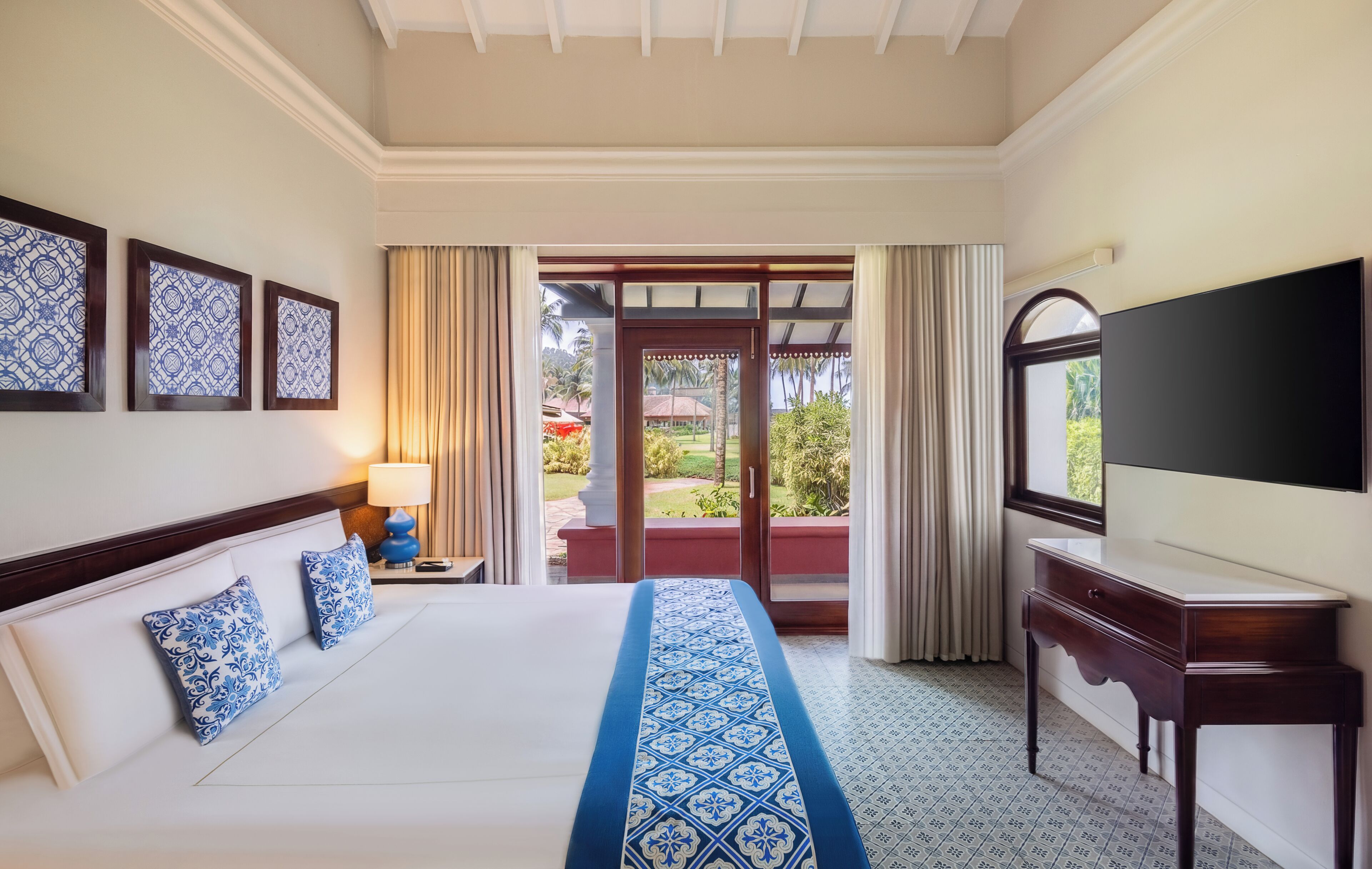 Habitación de hotel con cama, televisión, mesita de noche y vistas al exterior.