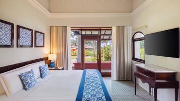 Habitación de hotel con cama, televisión, mesita de noche y vistas al exterior.