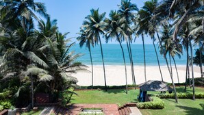 A beach view with palm trees and a thatched-roof structure. - Taj Holiday Village Resort & Spa (Candolim)