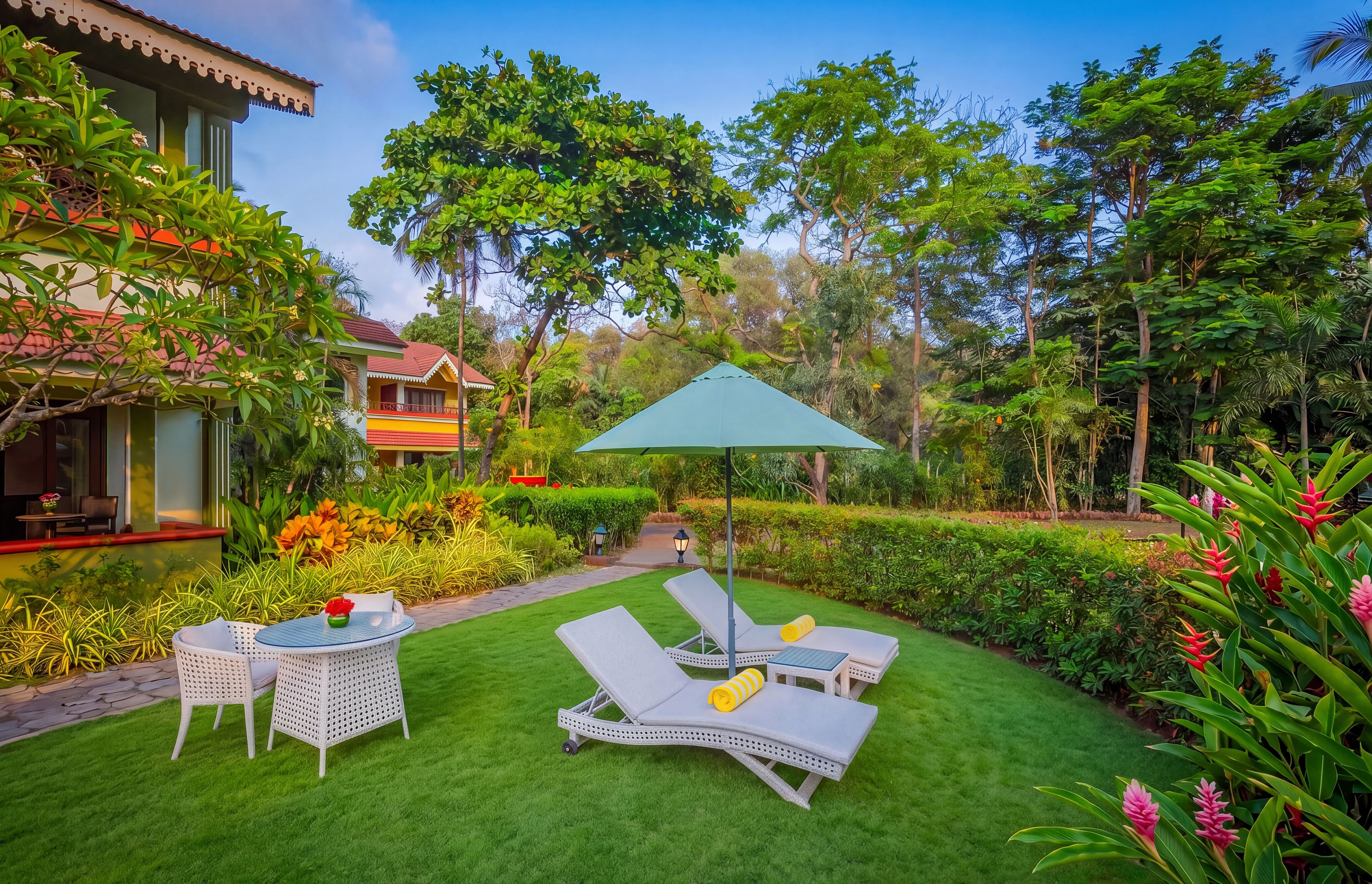 A well-maintained garden with a lawn, outdoor seating area, and a variety of plants and trees.