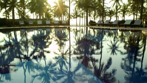A pool reflecting palm trees and lounge chairs. - Taj Holiday Village Resort & Spa (Candolim)