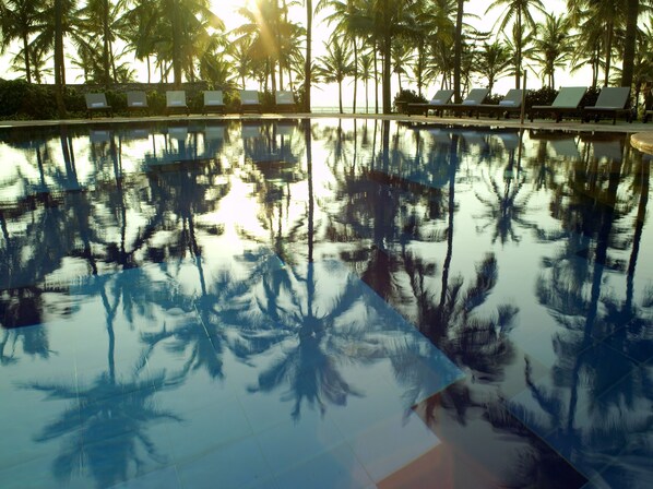 A pool reflecting palm trees and lounge chairs. - Taj Holiday Village Resort & Spa (Candolim)