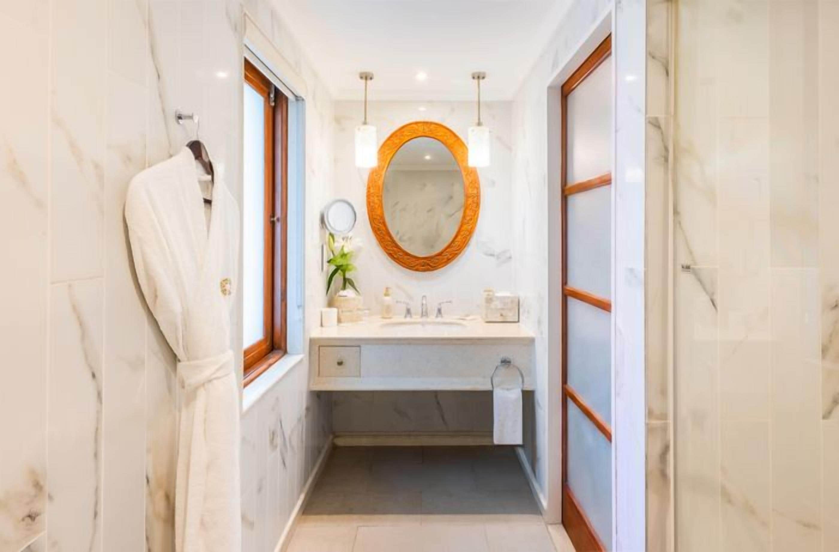 A bathroom with a marble floor, a wooden-framed mirror, and a towel rack.