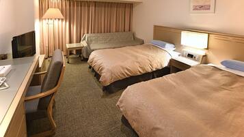 Ein Hotelzimmer mit Schreibtisch, zwei Betten, Fernseher, Lampe und einem fenster mit Vorhängen.