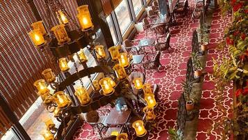 Un restaurant avec des tables et des chaises rondes, une moquette à motifs et des luminaires suspendus.