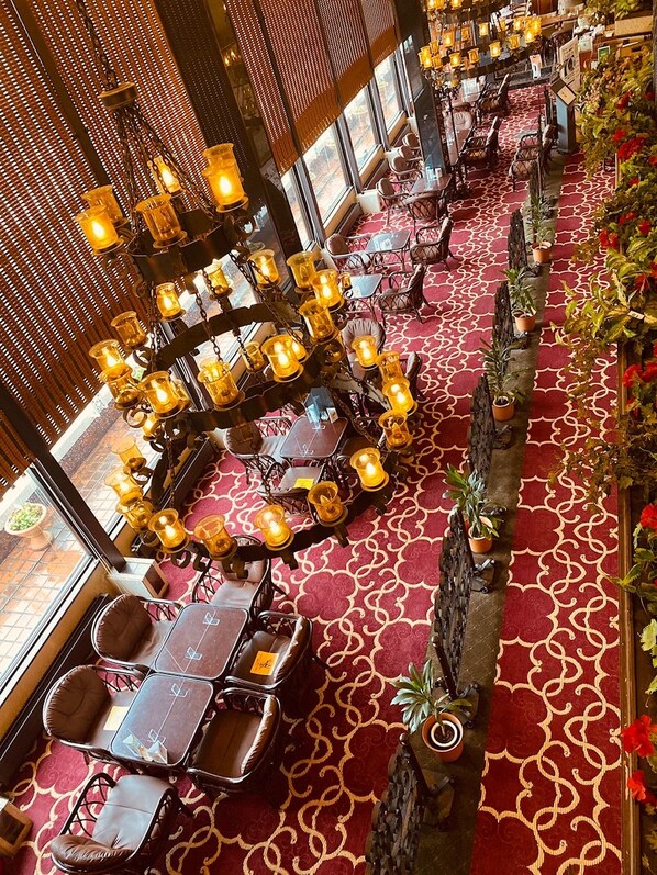 A restaurant with round tables and chairs, a patterned carpet, and hanging lights.