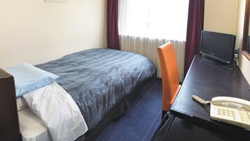 A hotel room with a bed, a desk with a telephone, a television, and a window with curtains.