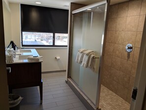 A bathroom with a shower, a sink, and a window.