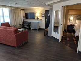 Habitación de hotel con un sofá rojo, un escritorio con computadora, un televisor y una cama con un tapete estampado.