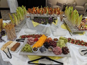 A buffet table with various food items and utensils. - Holiday Inn Champaign by IHG (Champaign)
