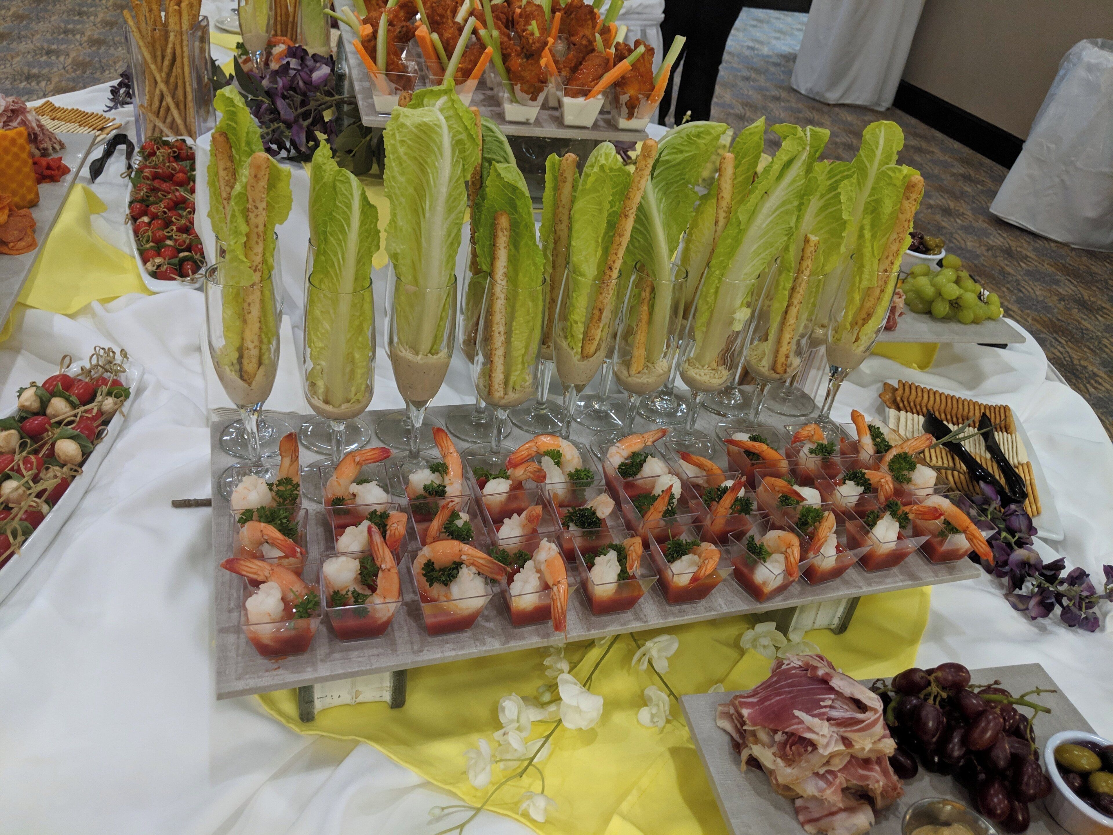A buffet table with various food items including shrimp appetizers, breadsticks, and a selection of cheeses.