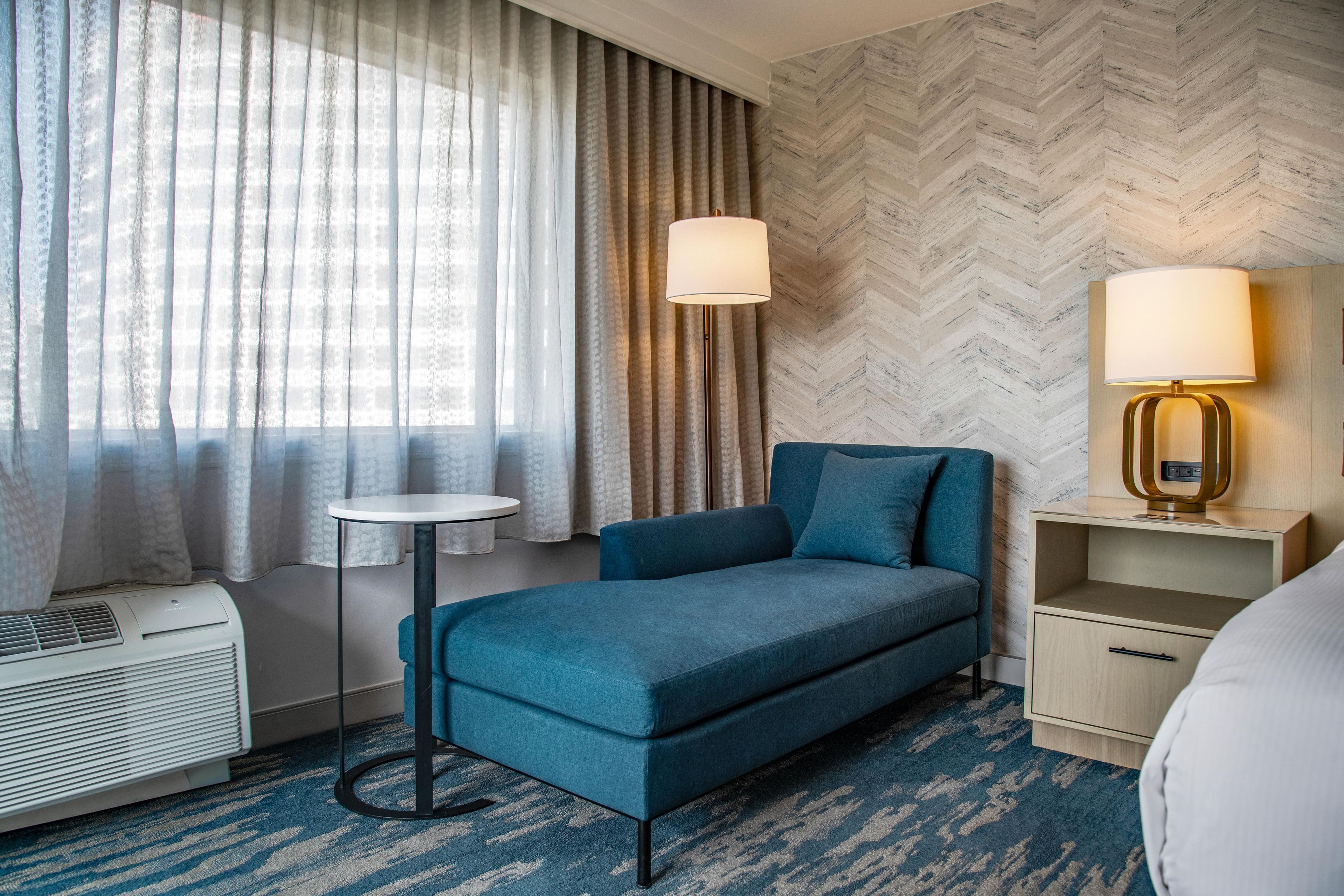 Una habitación de hotel con una cama, una mesita, una lámpara y un calefactor.