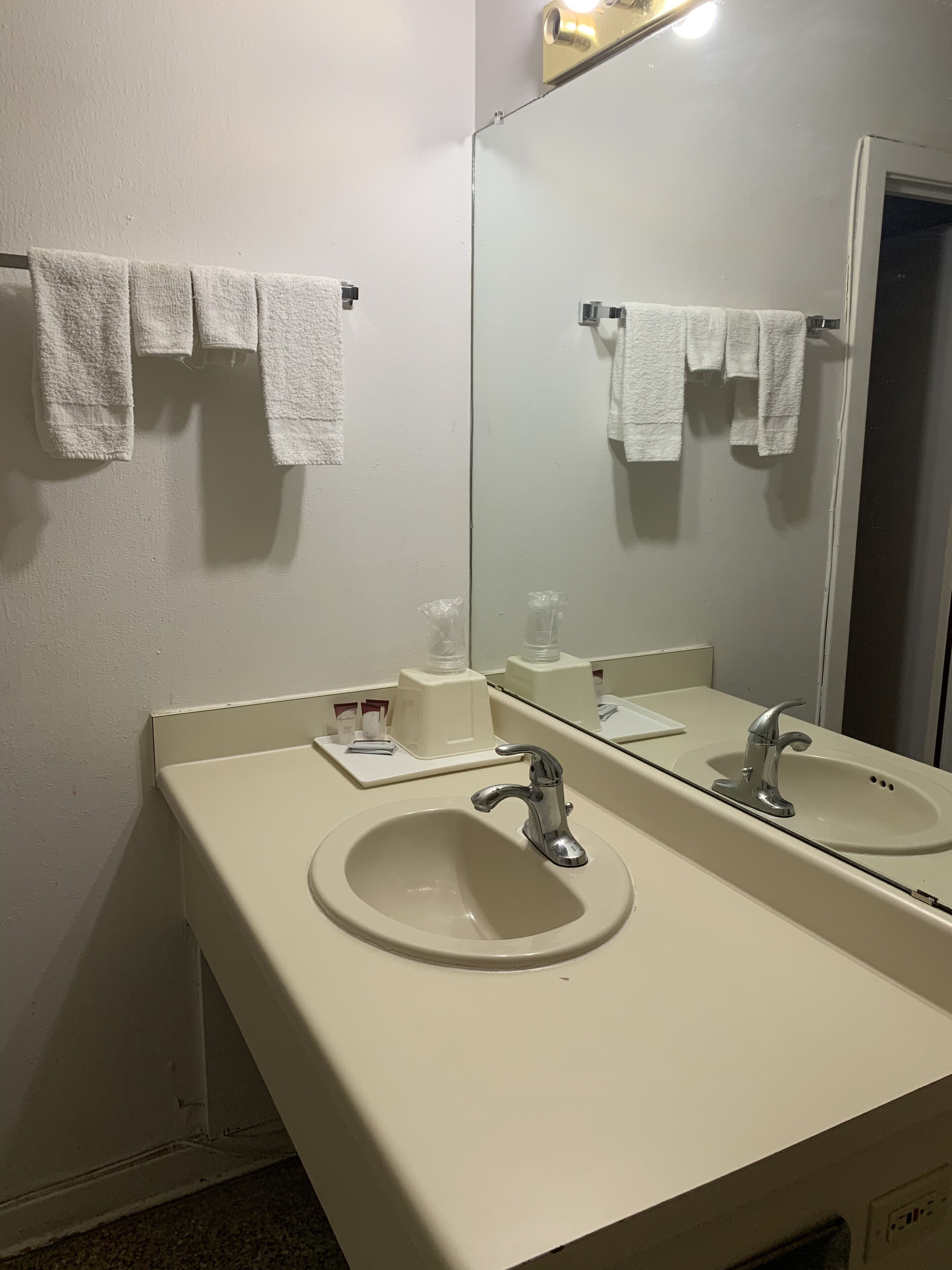 Een badkamer met twee wasbakken, een spiegel en handdoeken die aan de muur hangen.