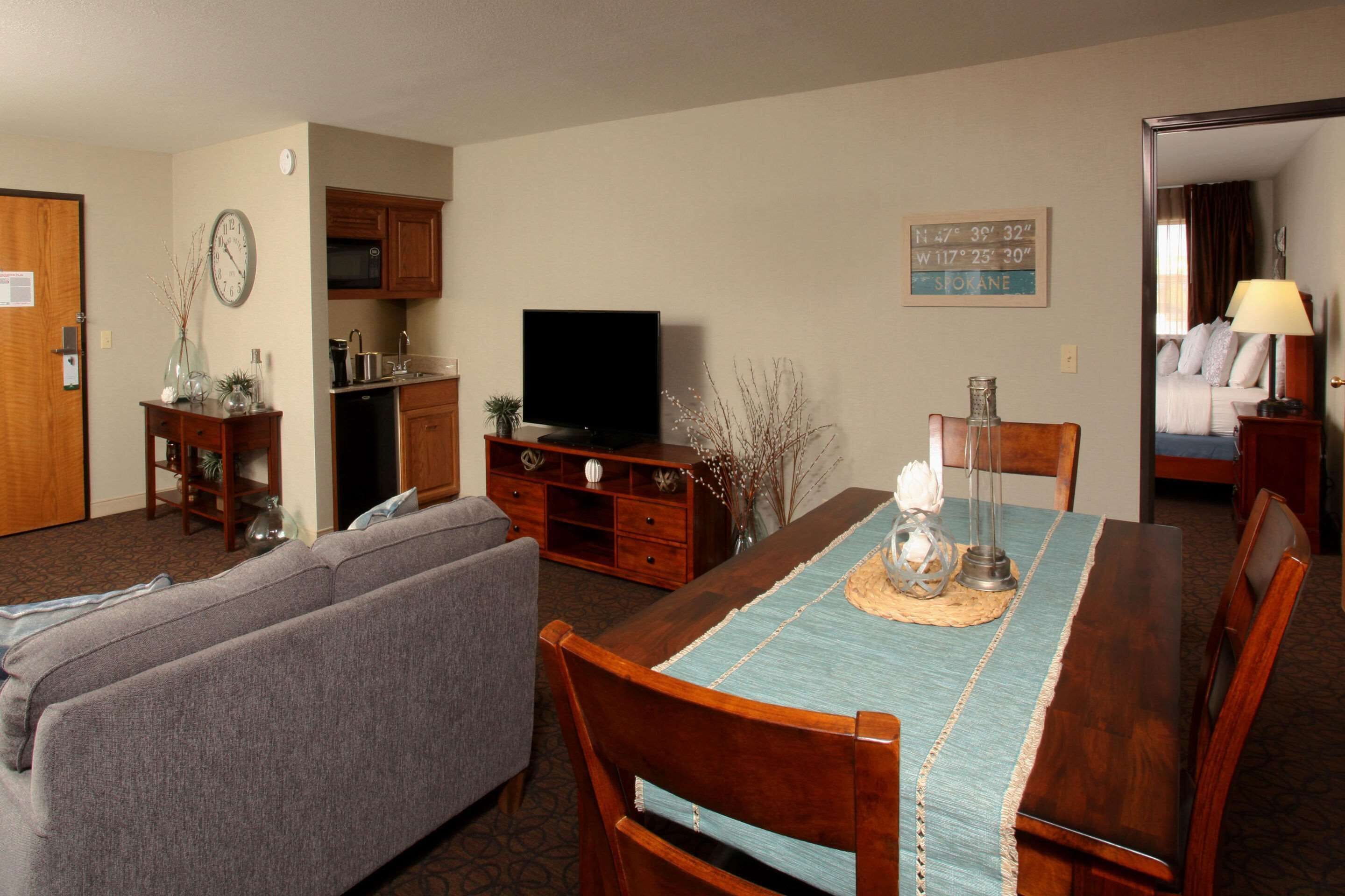 A living room with a TV, sofa, dining table, and kitchen area.