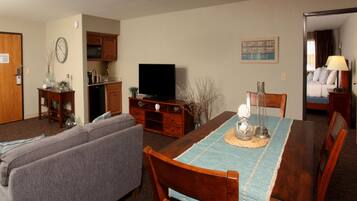 A living room with a TV, sofa, dining table, and kitchen area.