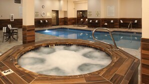 A hot tub with steam, a pool, lounge chairs, and a clock on the wall. - Quality Inn Oakwood (Spokane)