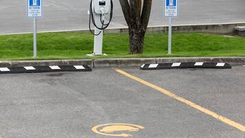 Een parkeerplaats met oplaadpunten voor elektrische voertuigen, aangeduid met blauwe borden en een laadpaal.