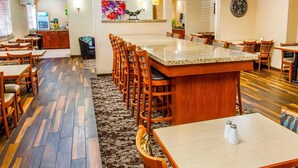 A modern kitchen with a central island, wooden chairs, and a patterned rug. - Quality Inn Oakwood (Spokane)