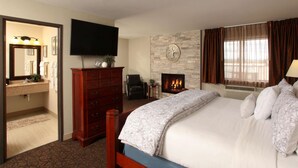 A hotel room with a bed, a dresser, a television, a fireplace, and a bathroom visible through an open door. - Quality Inn Oakwood (Spokane)