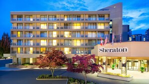 Un hotel Sheraton con varios pisos, balcones y una entrada bien iluminada.