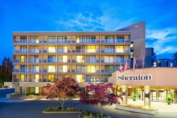 A Sheraton hotel with multiple floors, balconies, and a well-lit entrance. - Sheraton Vancouver Airport Hotel (Richmond)