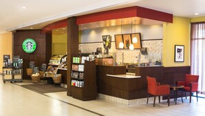Una cafetería Starbucks con mostrador, zona de asientos y diversos productos de café.