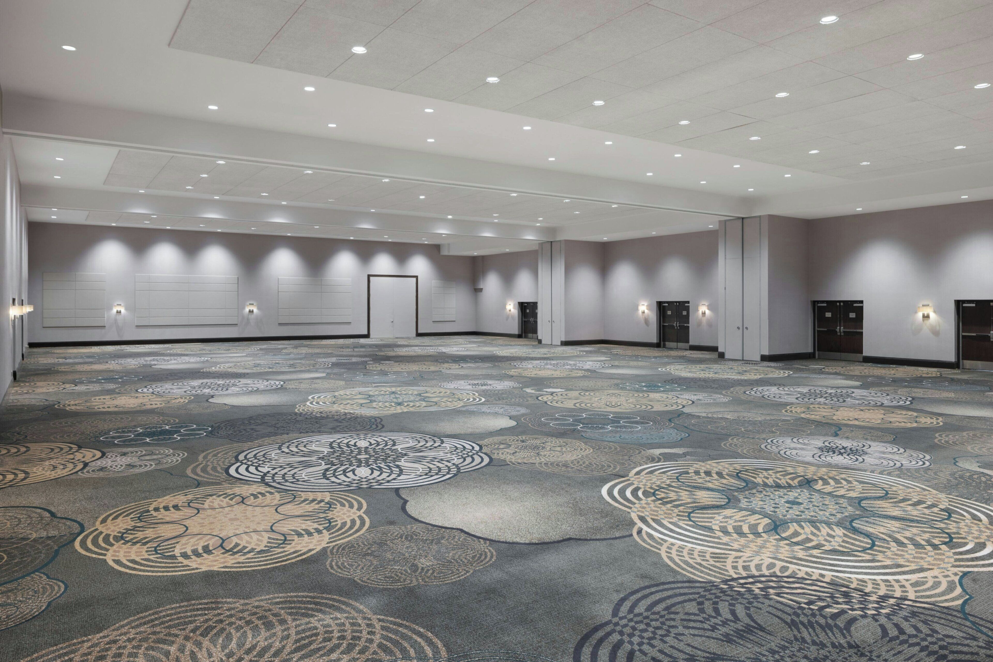 Un amplio salón de conferencias con alfombra estampada, iluminación empotrada y taquillas.