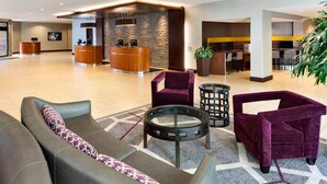 Vestíbulo de hotel con mostrador de recepción, zona de estar y bar.
