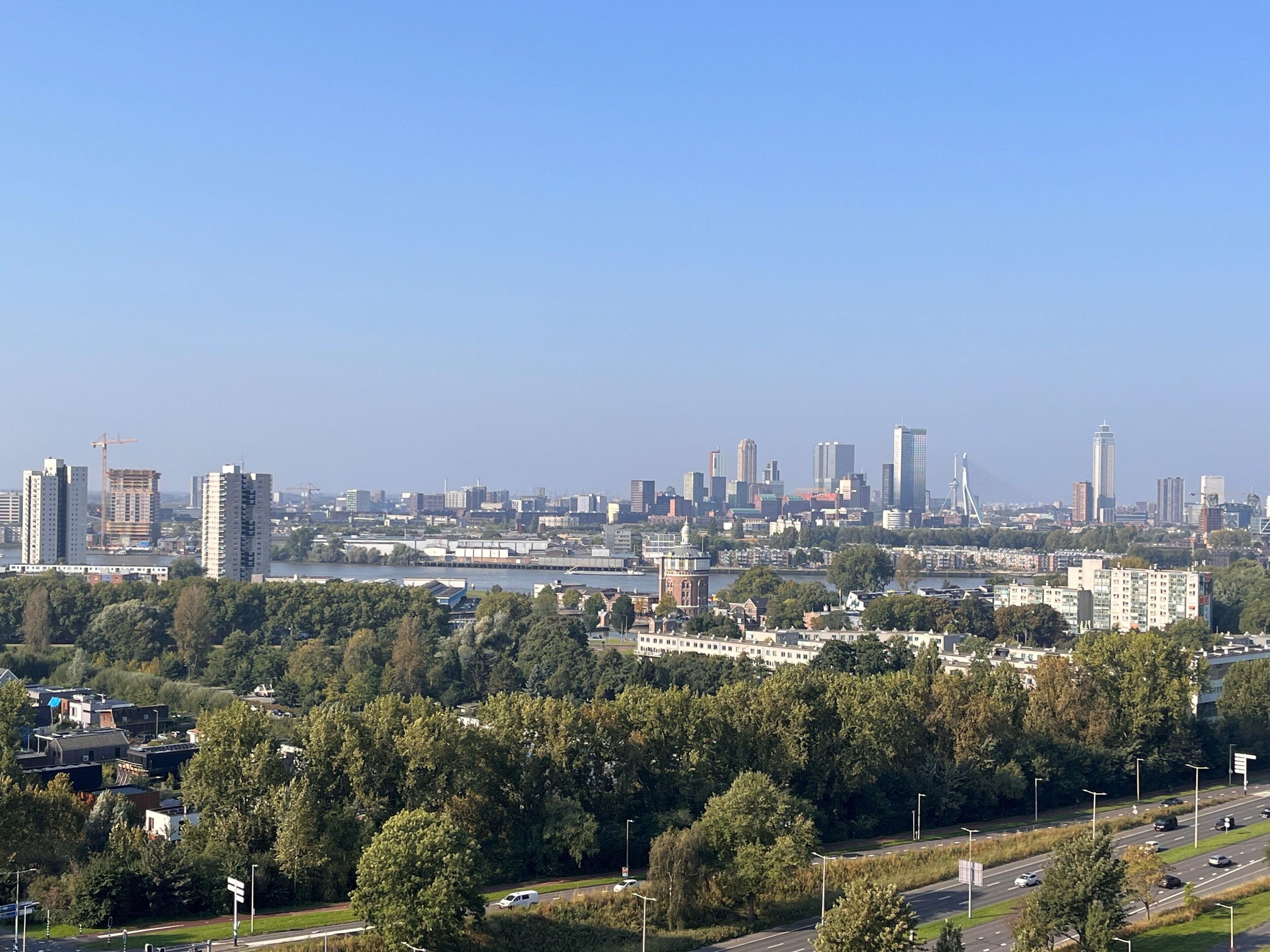 Stadsgezicht met wolkenkrabbers, een rivier en een brug.