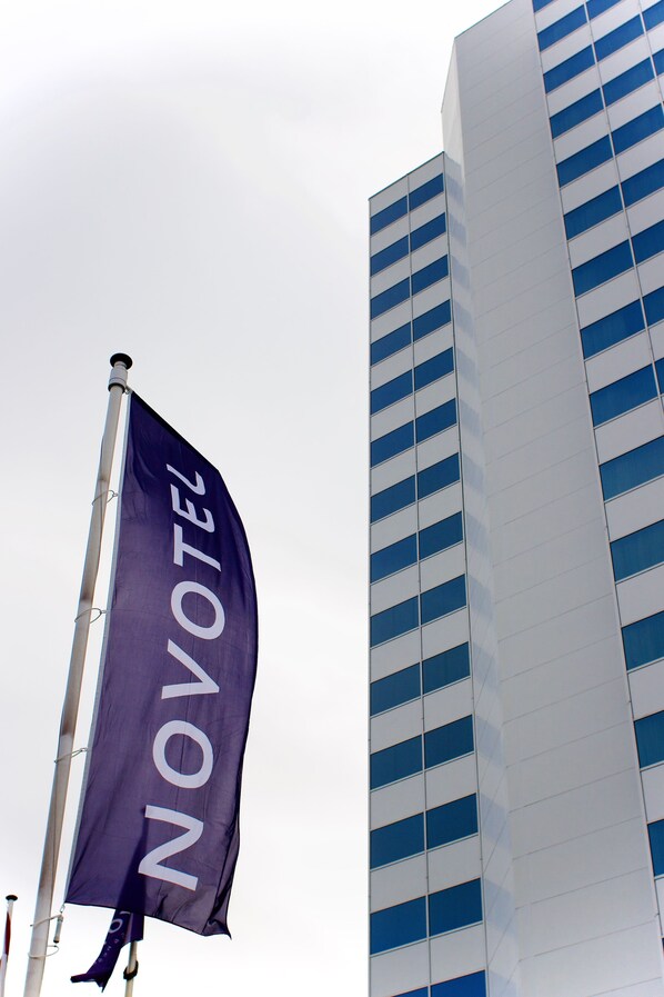 A flag with the word "NOVOTEL" on a flagpole, with a modern building in the background.