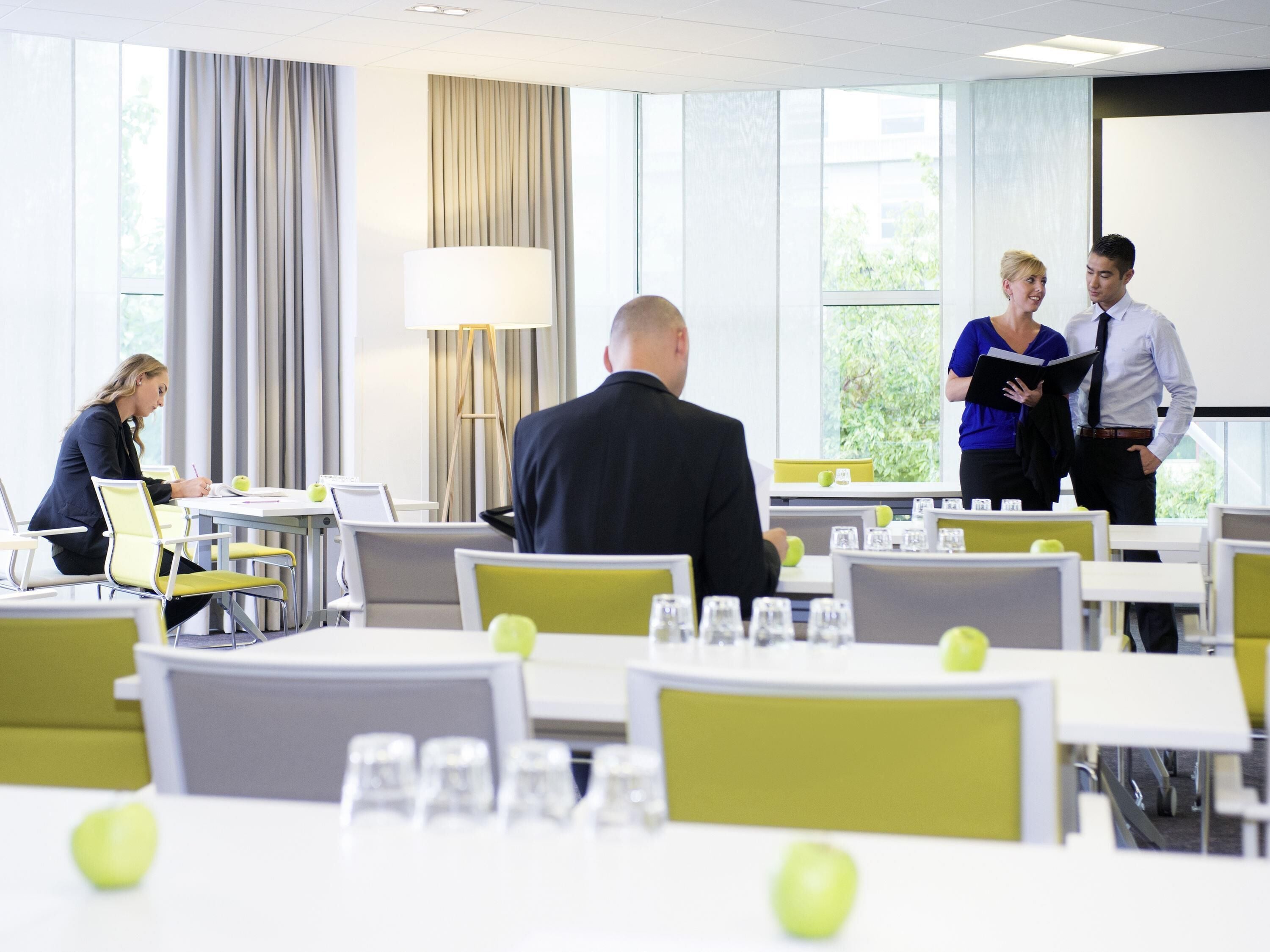 A modern conference room with tables, chairs, and a large window.