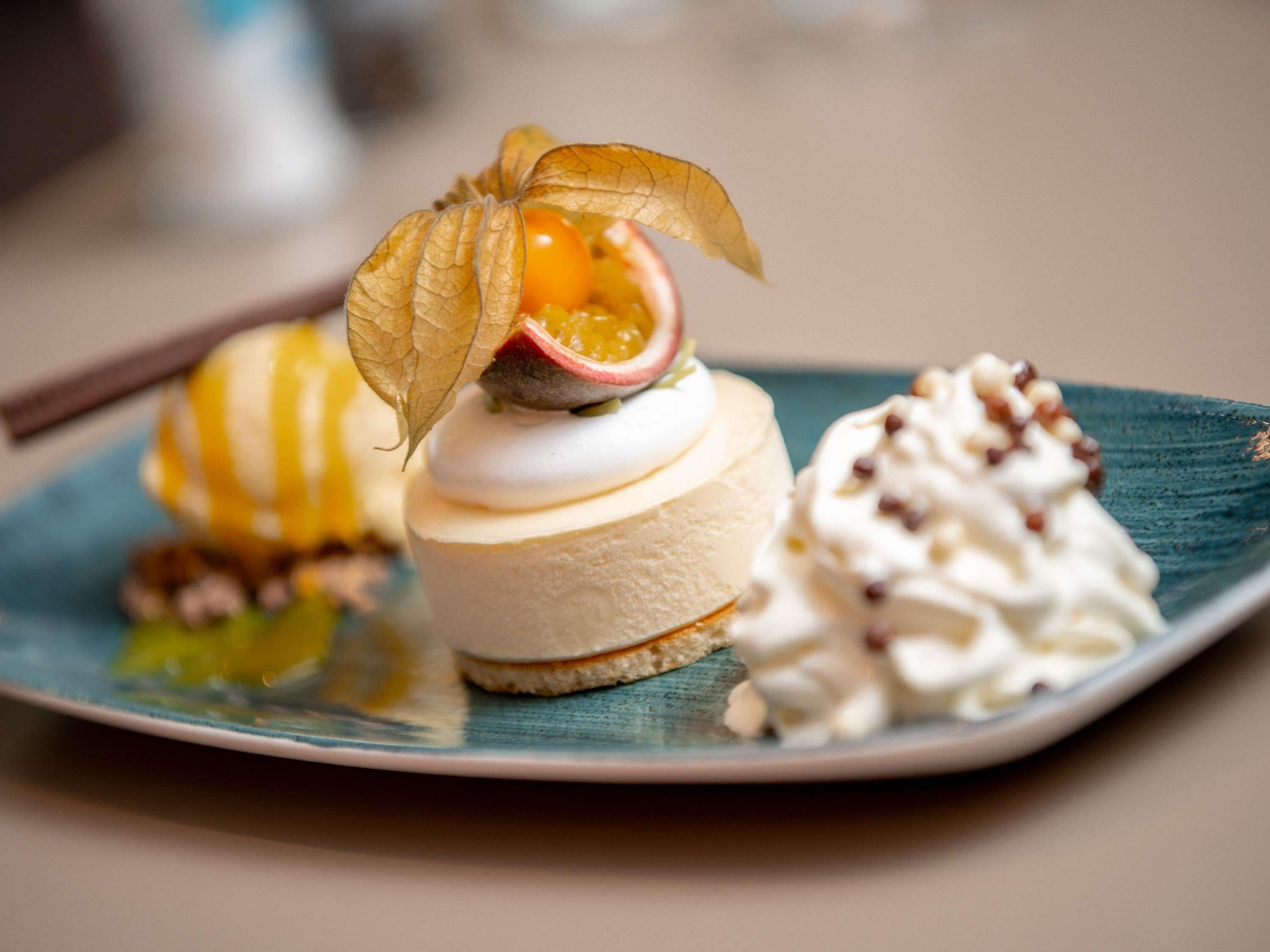 Ein Dessertteller mit einer gestreckten Torte, einer Obstgarnitur und einer Sahnehaube.