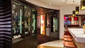 A modern bar area with glass display cases, wooden slats, and bar stools.