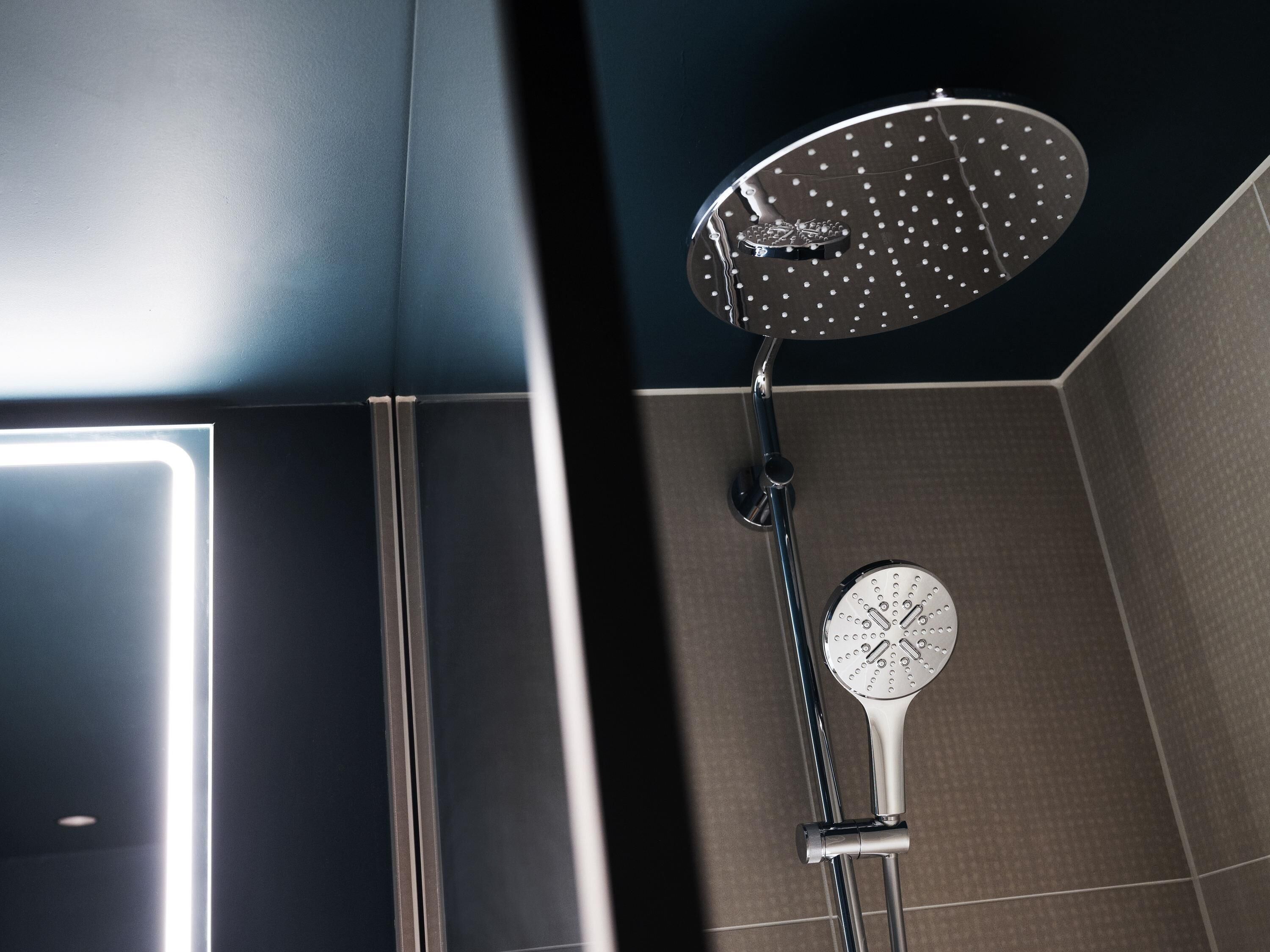 A shower with a round head and a handheld showerhead.