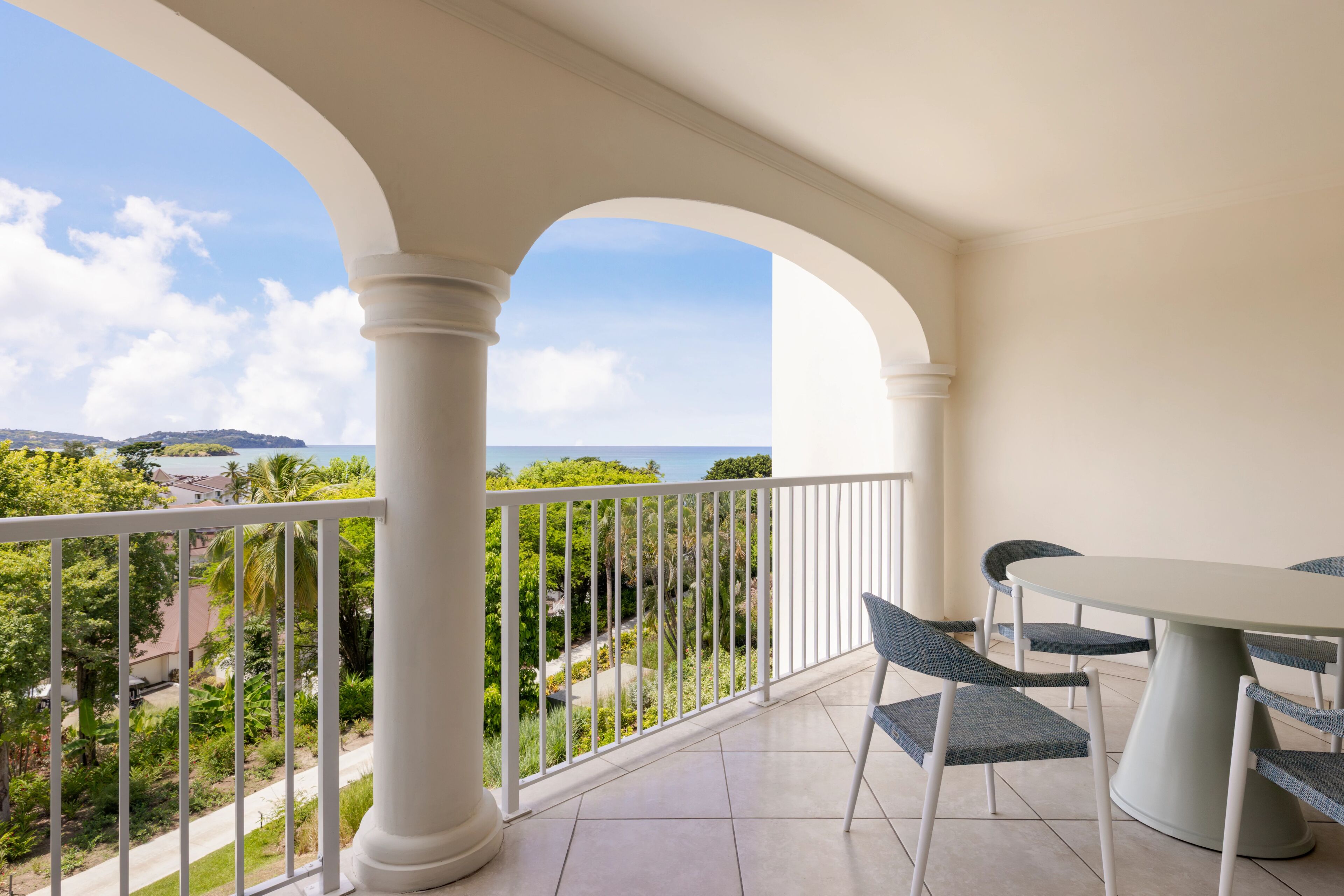 A balcony with a white railing, a round table, and four chairs.