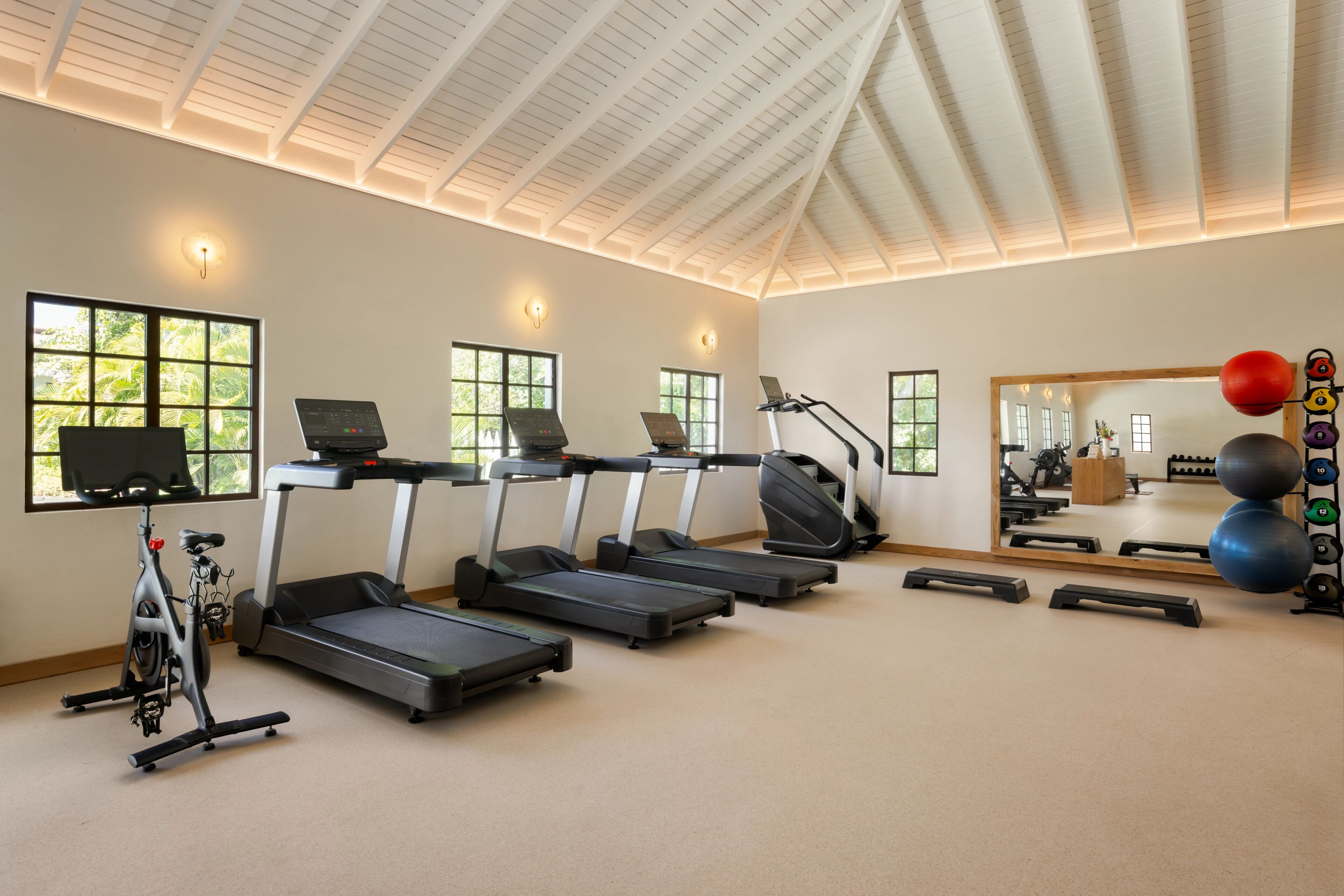 A gym with treadmills, an elliptical, a stationary bike, and a mirror reflecting the room.