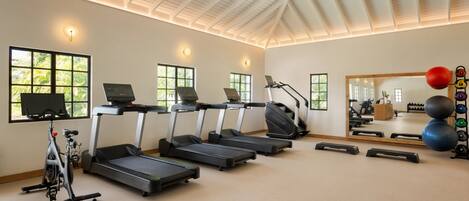 A gym with treadmills, an elliptical, a stationary bike, and a mirror reflecting the room.