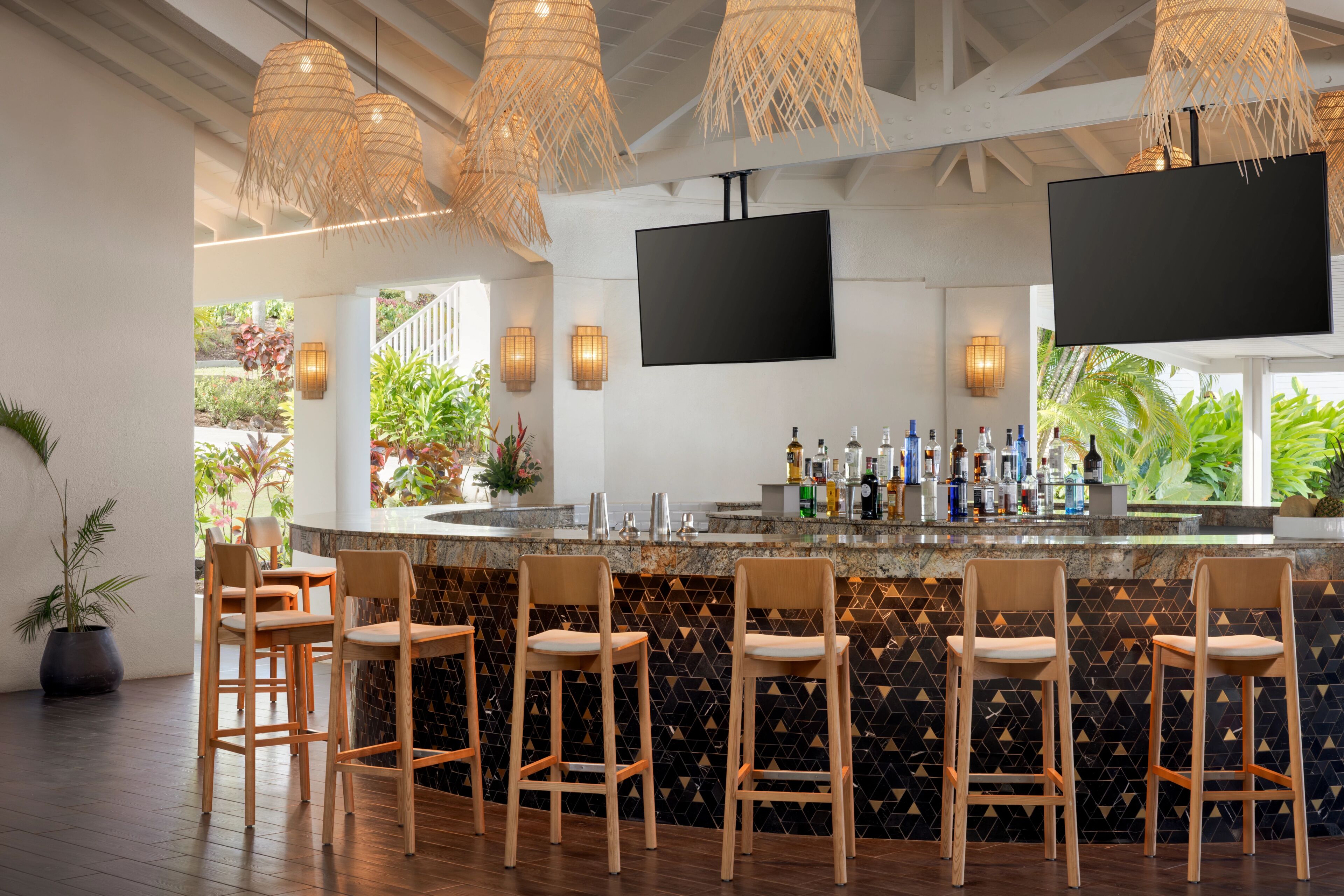 A bar area with wooden chairs, a counter with bottles, and a TV mounted on the wall.