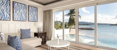 A hotel room with a large window, a sofa, a coffee table, and artwork on the wall.
