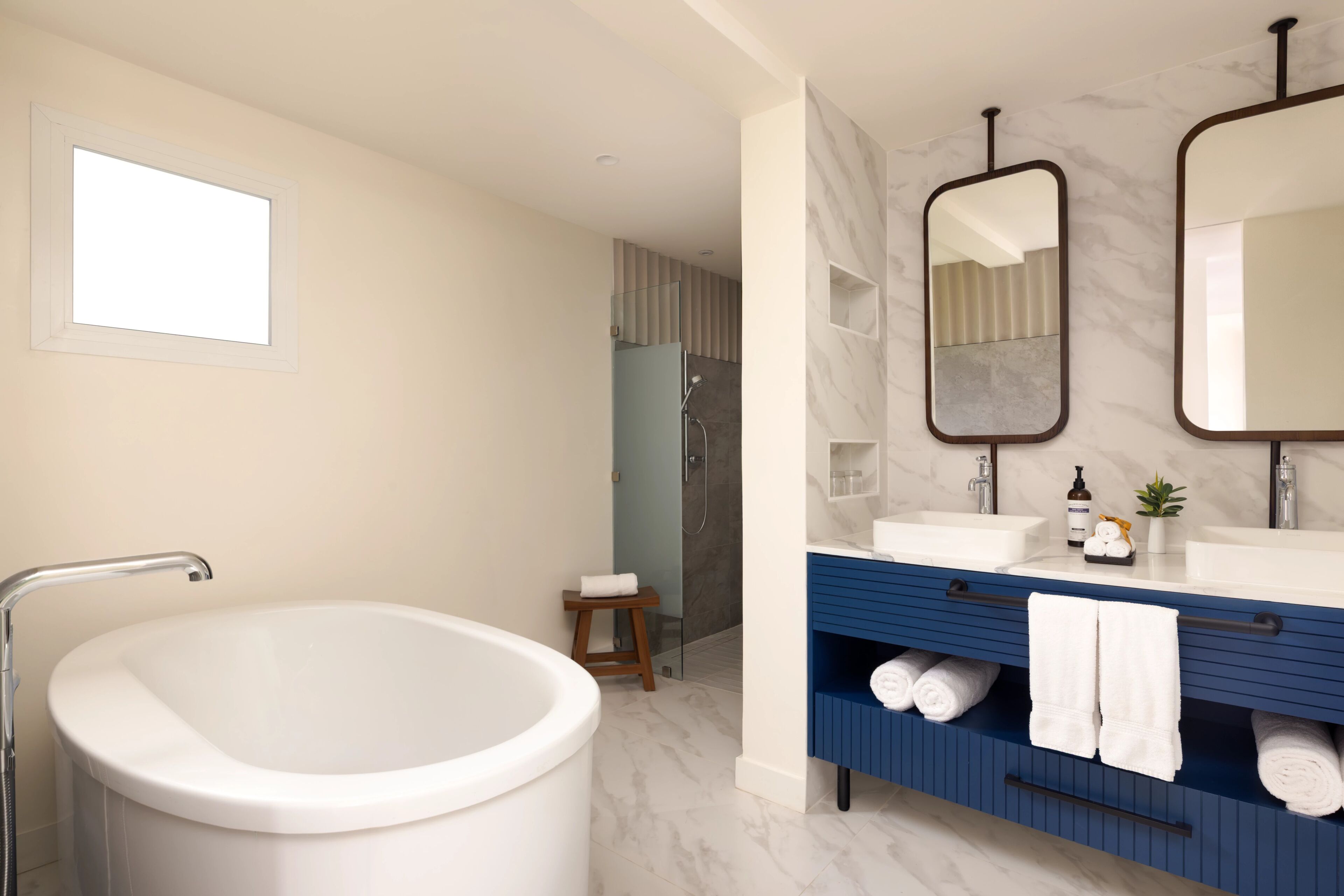 A modern bathroom with a freestanding bathtub, a vanity with a mirror, and a shower area.