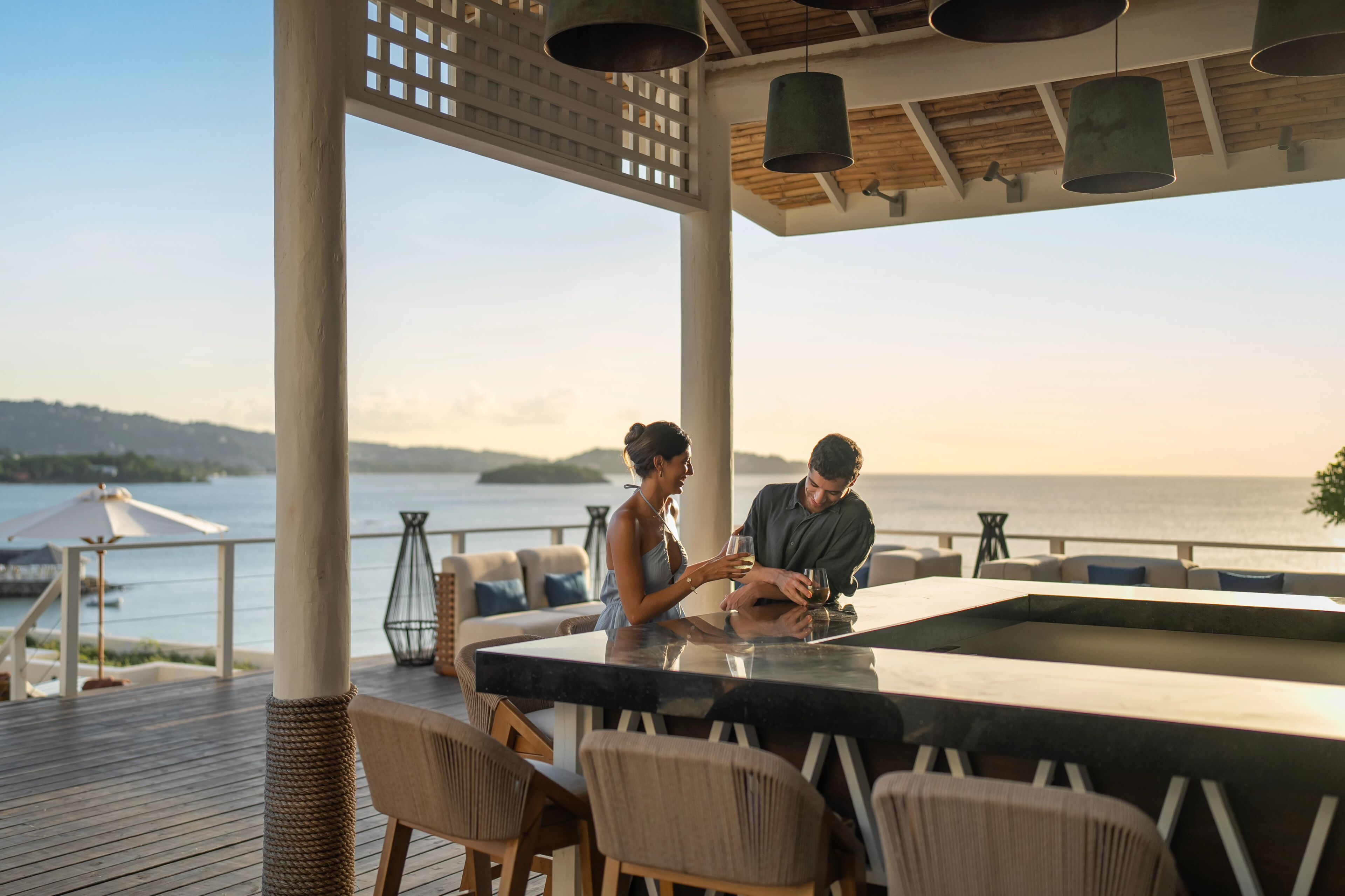 A couple at a bar with a view of the sea.