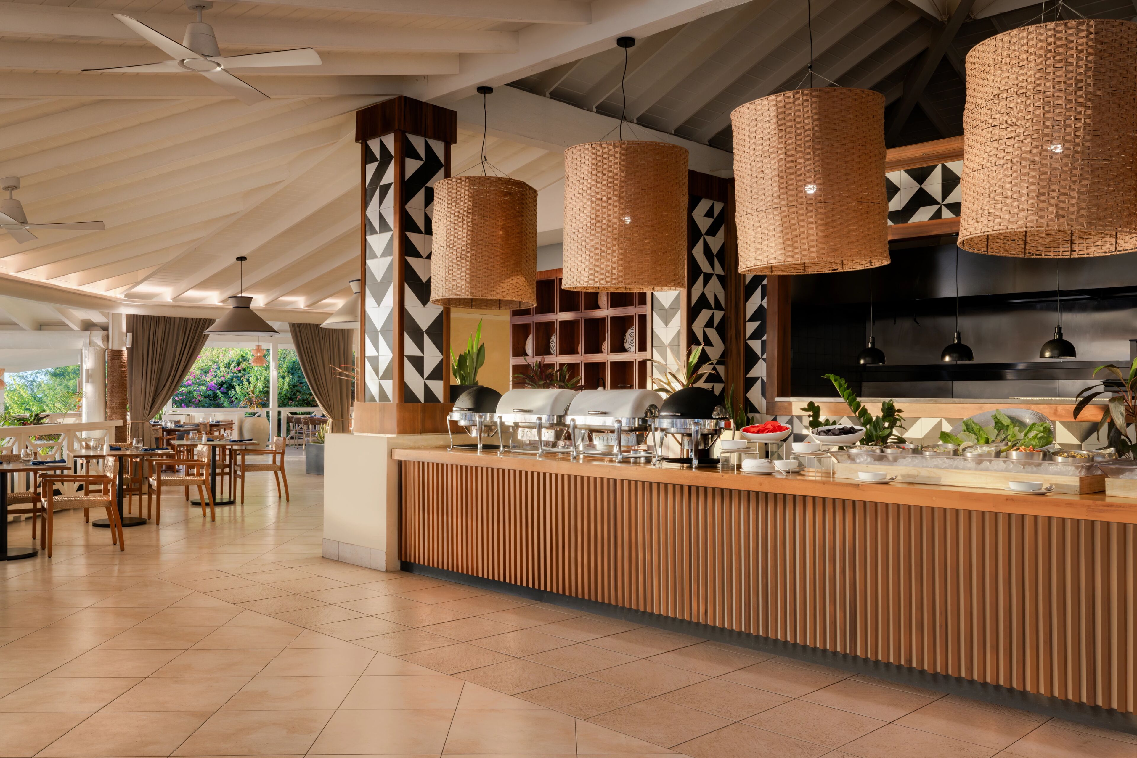 A spacious indoor area with a long counter, ceiling fans, and hanging wicker lamps.