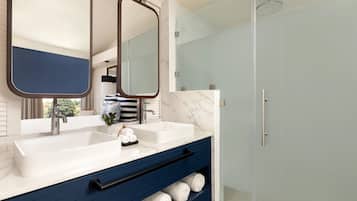 Un baño moderno con dos lavamanos, un espejo grande y una ducha.