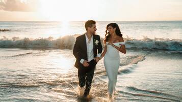 Una pareja caminando por la playa al atardecer.
