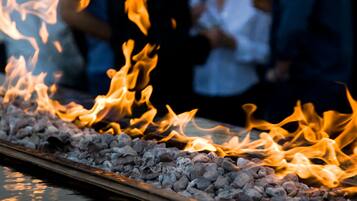 A fire feature with a metal grate and gravel, surrounded by people.
